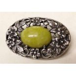 Sterling silver brooch with decorative pierced floral mount surrounding a polished stone cabouchon.