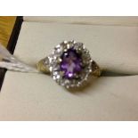 9ct gold ladies dress ring set with central oval amethyst surrounded by small diamonds. Size K.