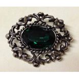 Oval brooch with a cut green stone.