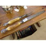 A bone handled carving set with white metal finials and bands with bull head decoration.