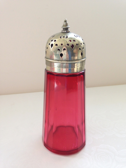 An antique cranberry glass sugar sifter with EPNS top.