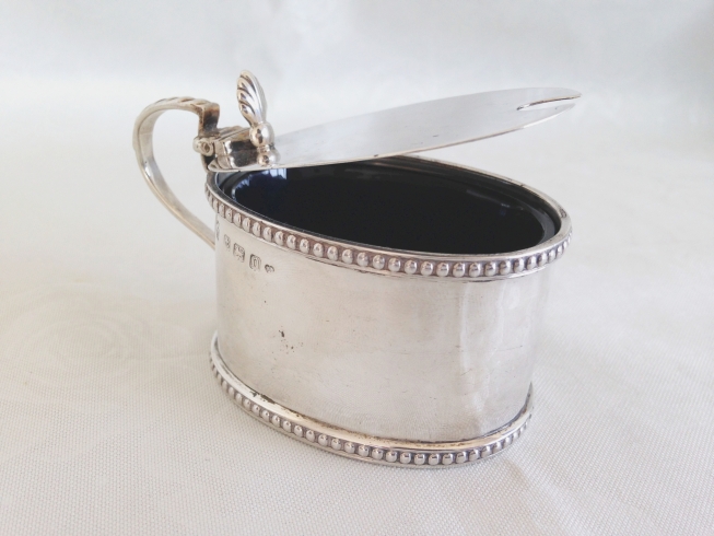 A silver mustard pot with hinged lid & blue glass liner, Birmingham 1912.