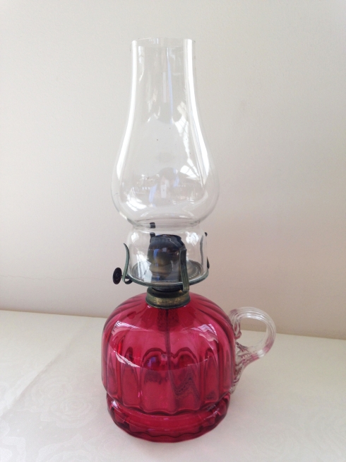 An antique cranberry glass hand held oil lamp.