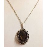 Large oval smokey quartz stone set in a decorative silver pendant mount on a silver chain.