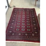 A vintage red patterned wool rug/carpet. Approx 190 x 127cm - fringed.