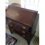 An Edwardian Oak bureau with conch shell inlaid decoration.