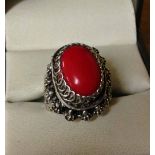 A white metal Egyptian 'poison' ring set with red oval cabouchon stone above poison compartment.