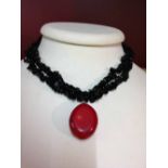 Double string black spinel stone necklace with large red polished coral pendant.