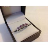 Pretty hallmarked 9ct white gold ring set with 5 rubies encircled by small diamonds. Size approx R