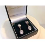 A pair of silver drop earrings set with crystals.