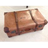 A vintage large brown trunk with leather corners and straps