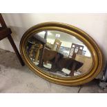 A vintage oval gilt framed mirror with bevelled glass.