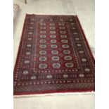 A vintage red patterned wool rug/carpet. Approx 190 x 127cm - fringed.
