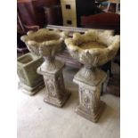 A pair of concrete garden planters on column plinths, 89cm tall.