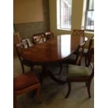 An extending yew dining room table with 8 chairs in red and green upholstery.