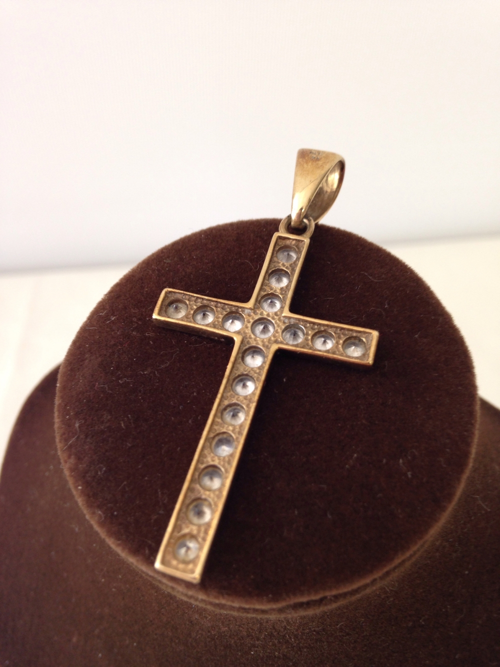 A large gold cross set with white stones measures approx 4cm long or 5.5cm to the top of the ring.