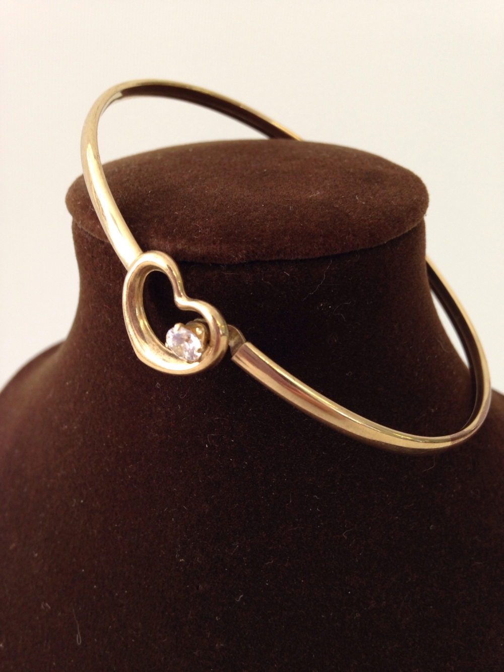 A hallmarked 9ct gold ladies bangle with heart design & white stone. Approx weight 3.2g.