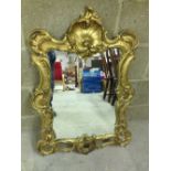 An ornate gilt framed mirror. 83cm tall.