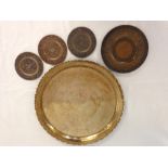 A Far Eastern brass tray with peacock decoration with 4 other smaller brass trays.