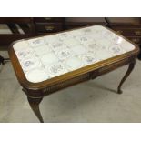 An oak table with Dutch tiles to top, carved legs and cane panels to side.