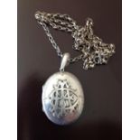 Large oval silver locket 4cm long on a 28 inch white metal belcher chain. Entwined letters affixed