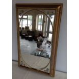 A continental mirror with pierced border decoration and lights behind.