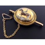 A 9ct gold oval brooch set with an oval crystal painted horse racing jockey. Birmingham 1819.