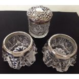 A pair of antique cut glass salts with HM silver rims and a cut glass rouge pot with a silver lid HM