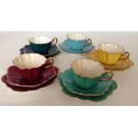 5 Royal Stuart Harlequin china trio's each in a different colour with gilded rims and handles.