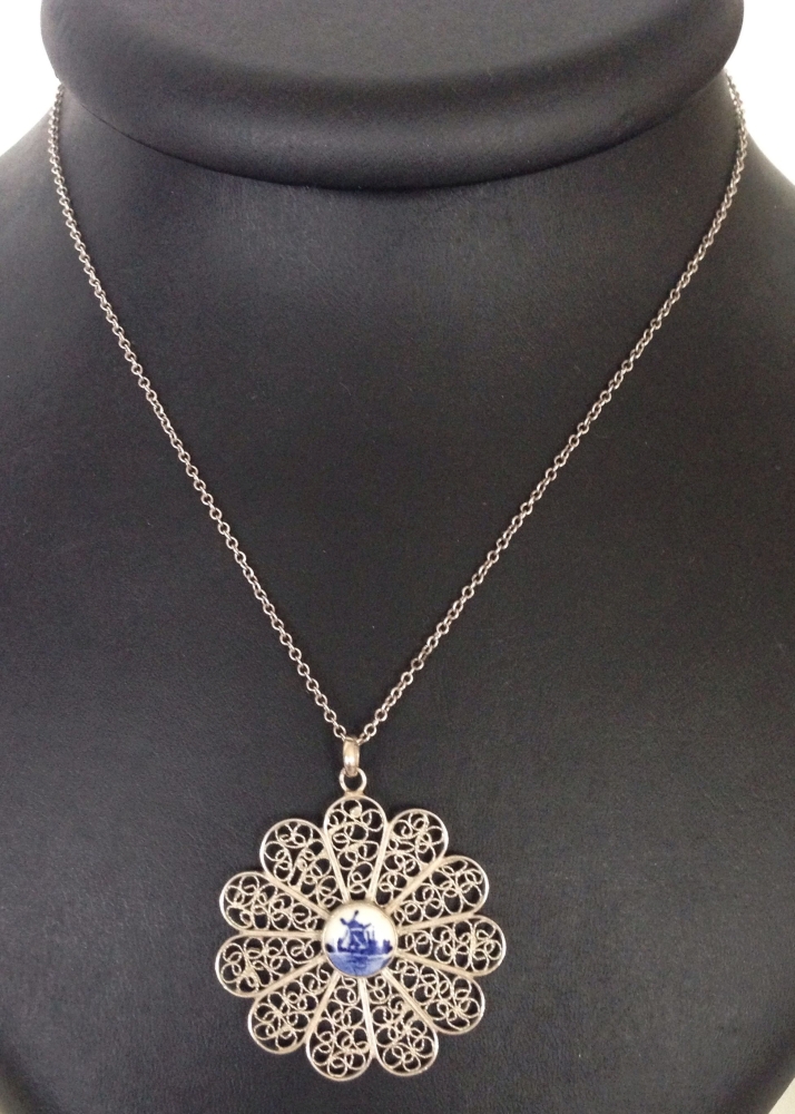 A filigree silver flower design pendant with a ceramic centre depicting a Dutch Delft windmill,