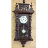 A wooden cased wall clock with enamel dial and pendulum. In working order with key.