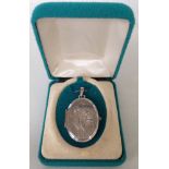 An oval silver locket with tulip flower design engraved front approx 3cm long - on a silver chain.