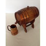 Oak spirit barrel with copper banding on stand and wooden tankard with brass bands.