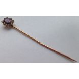 A Victorian gold stick pin set with a central oval amethyst surrounded by 6 seed pearls. Tests as