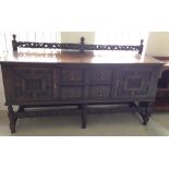 A Dark oak sideboard with carved panels and front & top carved rails. 182cm long.