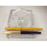 A glass inkwell with a yellow Platignum 'Silverline' fountain pen, and another unmarked fountain