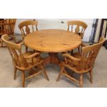 A circular pine kitchen table with 4 pine carver chairs.