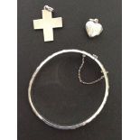 3 pieces of silver jewellery - an engraved bangle, a heart shaped locket and a cross.