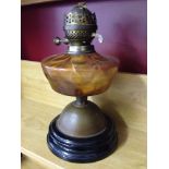 A vintage oil lamp with orange glass reservoir - no chimney.