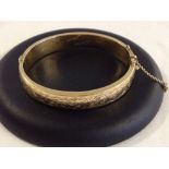 Hallmarked 9ct gold bangle with engraved decoration. Safety chain broken, 2 slight dents and the