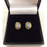 A pair of gold stud earrings set with oval opal stones.