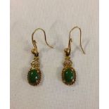 A pair of 9ct gold drop earrings set with green stones.