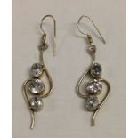 White metal drop earrings set with 2 oval and 1 round clear stones to each.