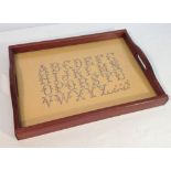 A vintage alphabet sampler set into a tray.