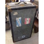 A large vintage grey travelling trunk with destination labels.