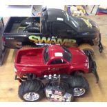 2 large radio controlled pick-up trucks. A black New Bright 'Swamp Dawg' and an EzTec red