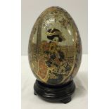 A Satsuma egg on wooden stand. 20cm tall including base. 2 panel depiction of a geisha.