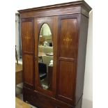 An Edwardian wardrobe with central door with oval mirror, cross banding and shield design inlay.