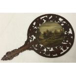 A vintage wooden handheld fan/face screen with handpainted oil of a riverbank in the centre.