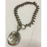 A large Victorian silver locket with raised buckle decoration on an unusual ball & link chain.